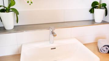 A bathroom with a white sink, a mirror, and two potted orchids.
