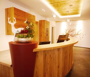 Un comptoir d’accueil avec un revêtement en bois, une sculpture de cerf blanc et un arrangement floral.