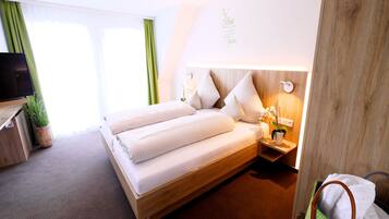 Ein Hotelzimmer mit einem großen Bett, einem Nachttisch mit Lampe, einem Fernseher und einer Zimmerpflanze.