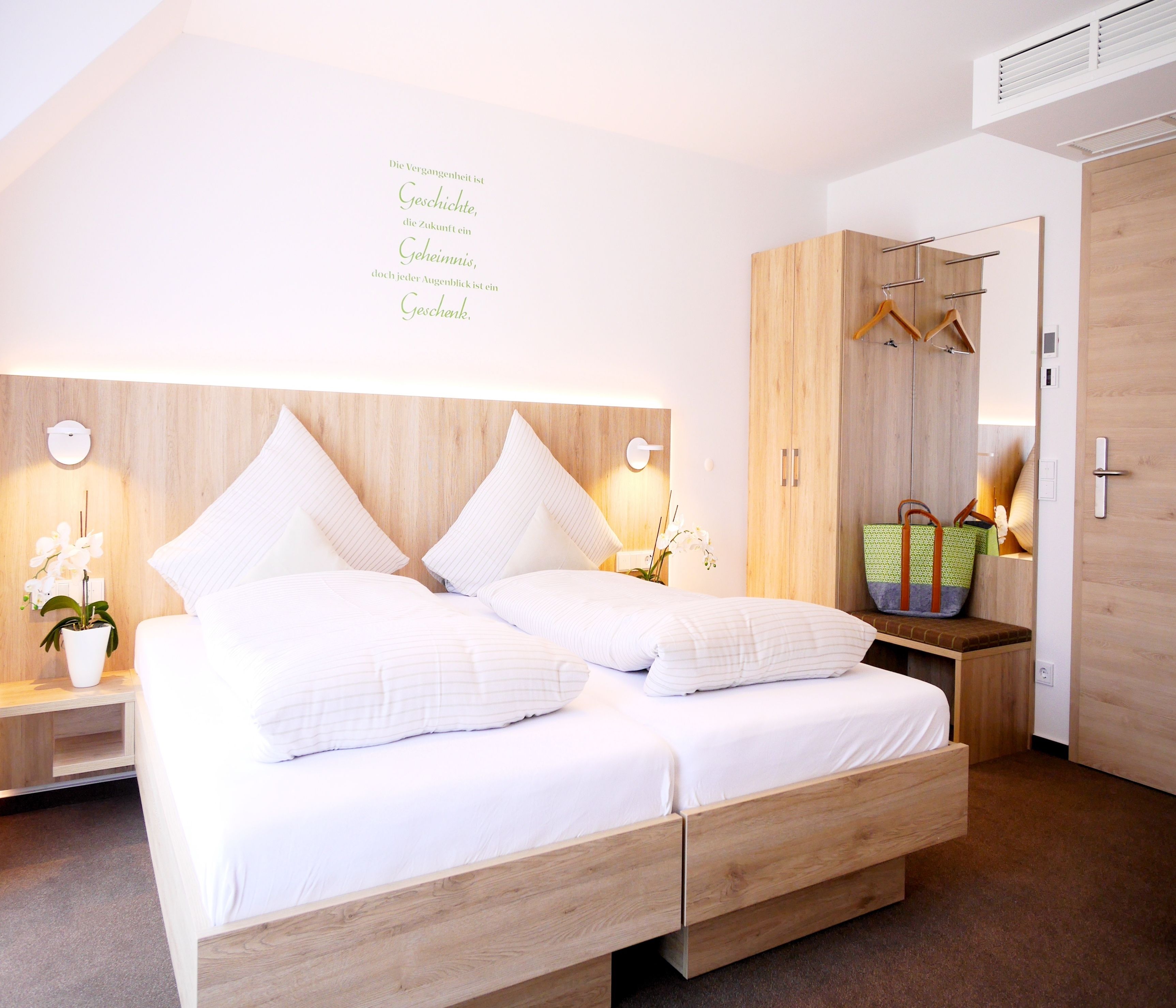 Un dormitorio moderno con cama de madera, mesitas de noche, un armario y un espejo.