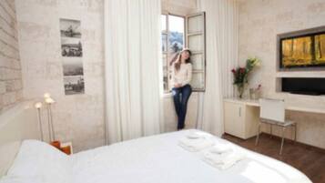 A modern hotel room with a large bed, a desk, and a window with curtains.