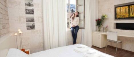 A modern hotel room with a large bed, a desk, and a window with curtains.