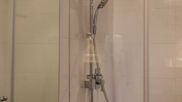 A modern bathroom with a glass-enclosed shower, a sink with a yellow soap dispenser, and a mirror.