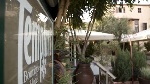 Placa para o 'Boutique Hotel', com área de estar ao ar livre e plantas em vasos.