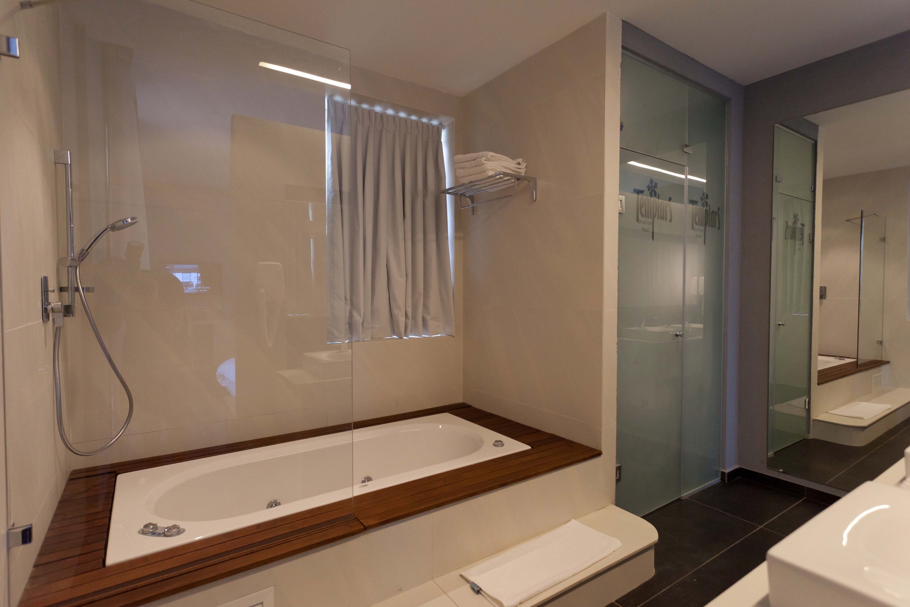 Un baño moderno con una bañera grande, cabina de ducha de vidrio y pared divisoria de vidrio.