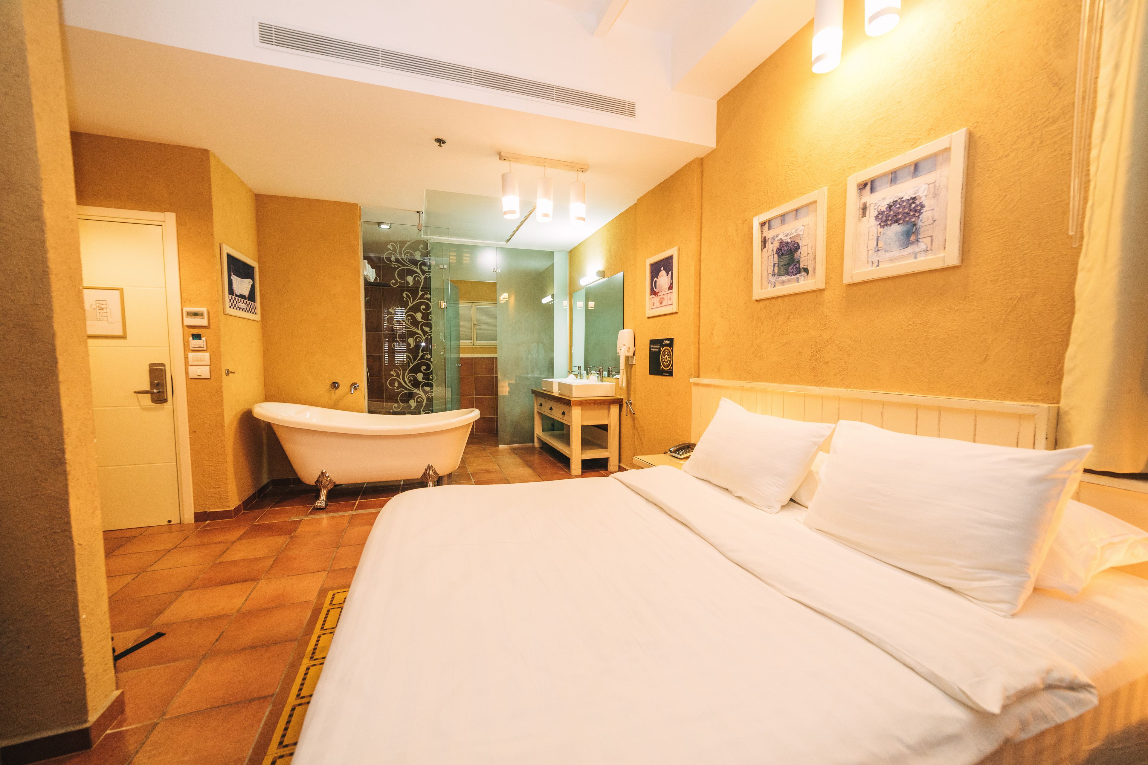Una habitación de hotel con una cama grande, una bañera, un tocador y un espejo.