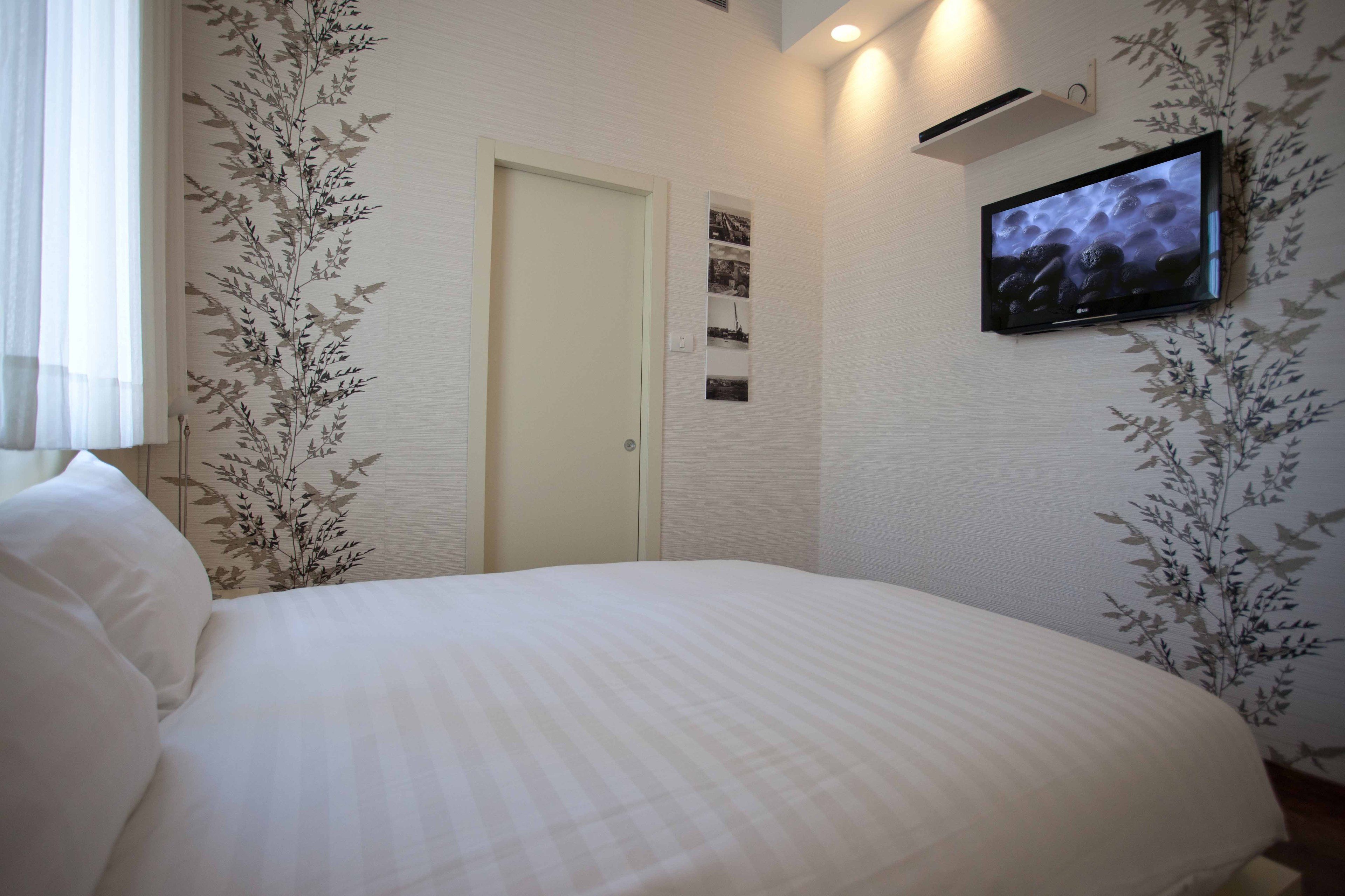 A bedroom with a large bed, a television mounted on the wall, and a door with a small photo gallery above it.