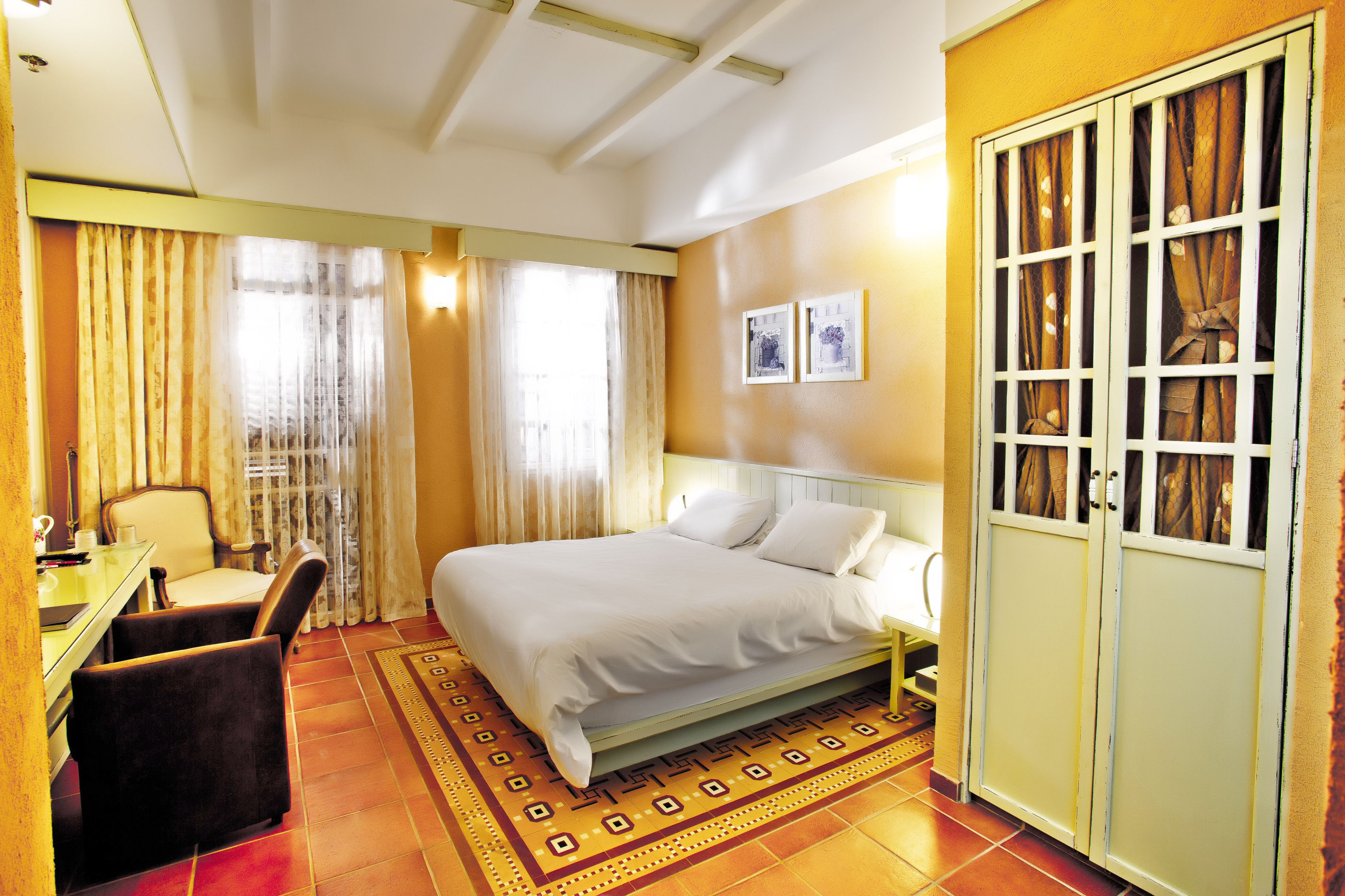 A hotel room with a bed, a desk, a chair, and a wardrobe.
