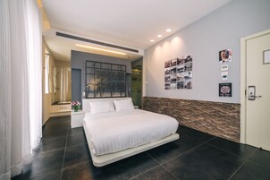 A modern hotel room with a large bed, a shower area, and a wall-mounted artwork.