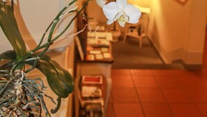 Un pasillo con una escalera, un jarrón con flores blancas y una cálida lámpara.