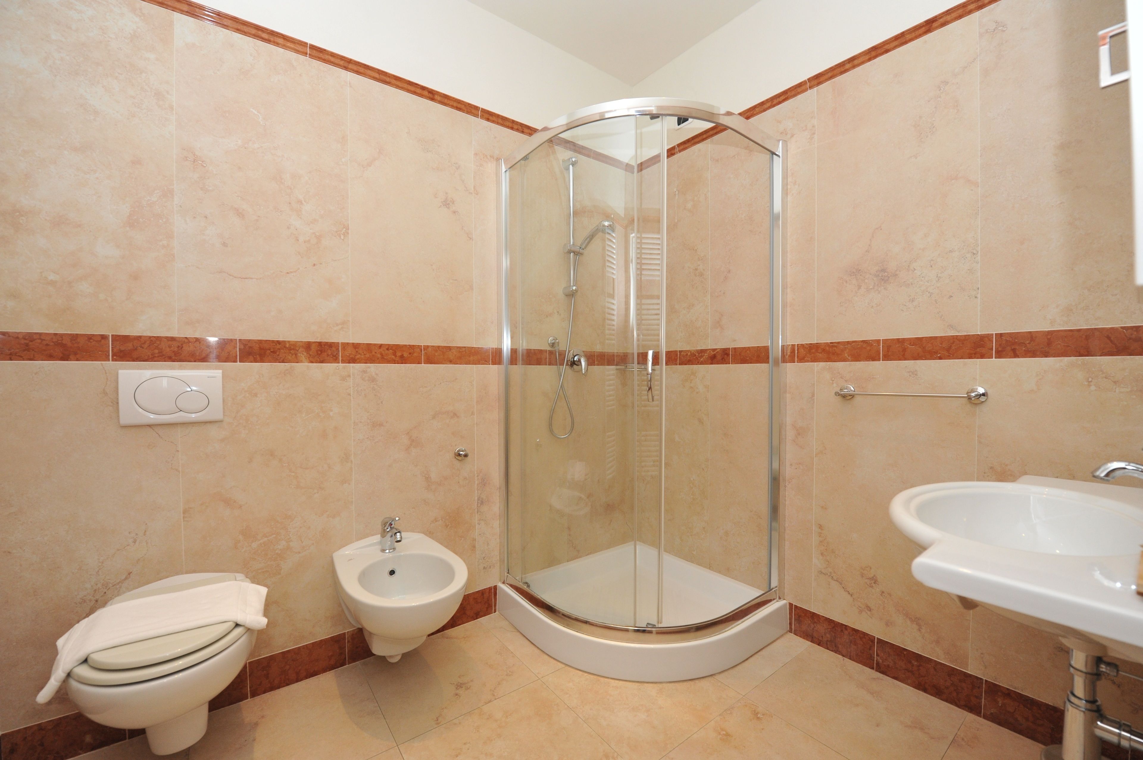 A bathroom with a glass-enclosed shower, a bidet, a toilet, and a sink.