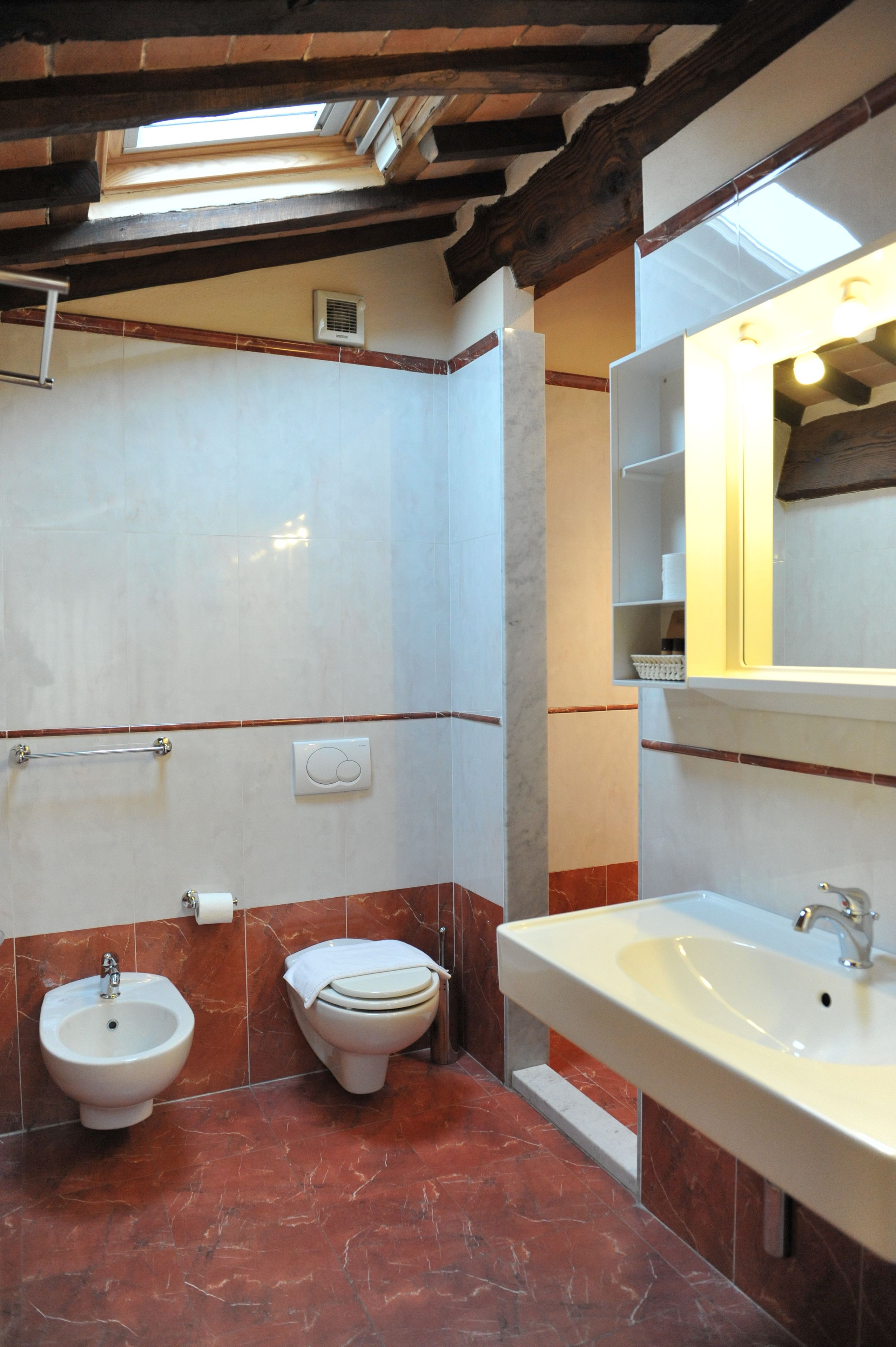 Une salle de bain équipée d’un bidet, de toilettes et d’un lavabo, avec des murs carrelés et un plafond en bois.