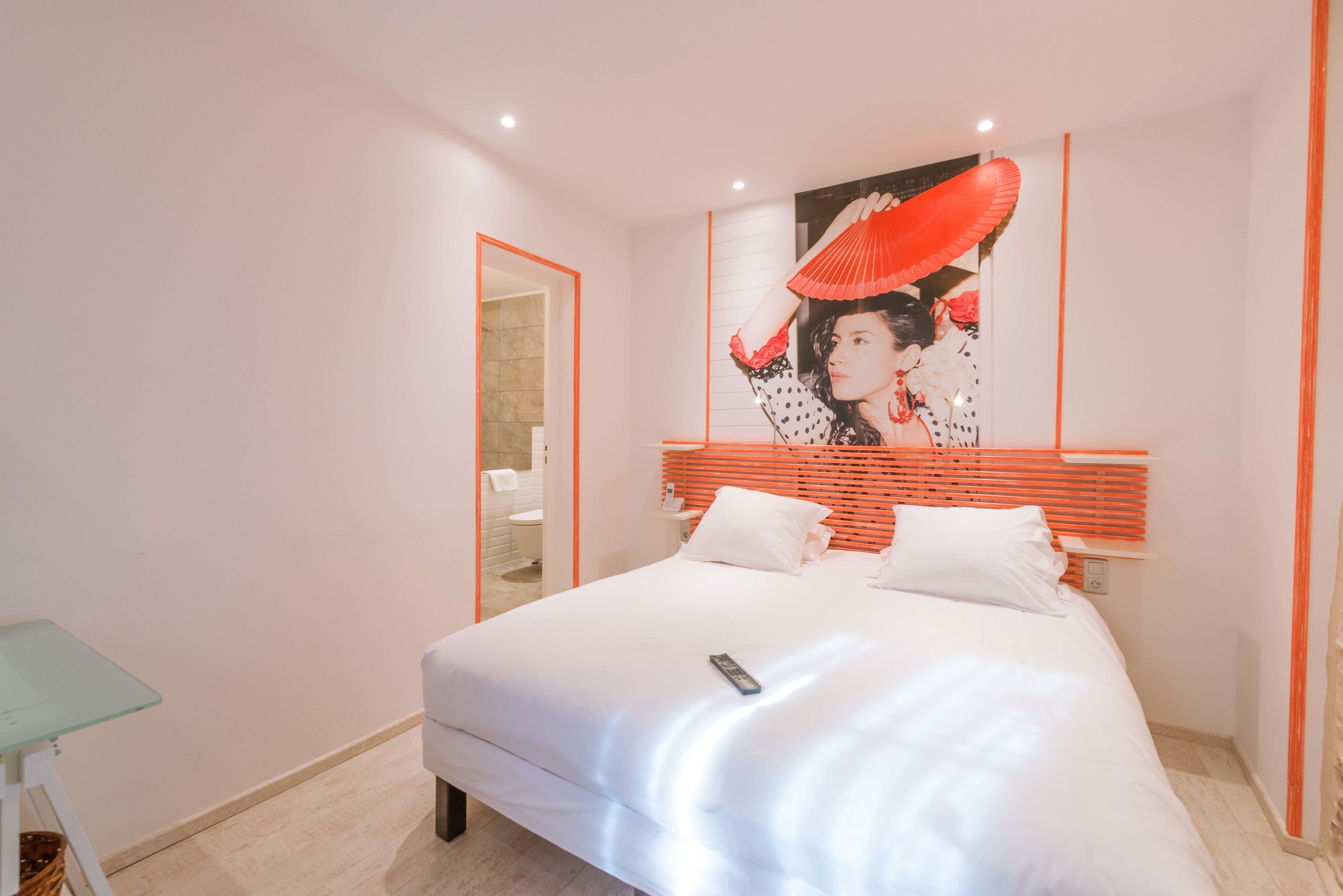 A modern bedroom with a large bed, a bedside table, and a wall-mounted artwork.