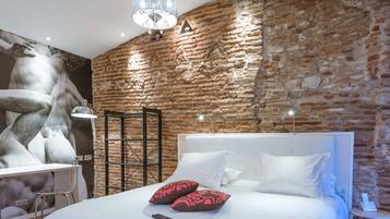 Een slaapkamer met een groot bed, een stenen muur en een kroonluchter.