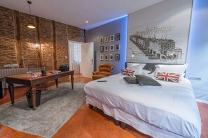 Un dormitorio con una cama, un escritorio, una silla y una pared decorada con cuadros.