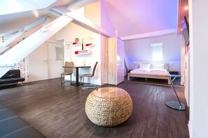 Un dormitorio estilo loft moderno con techo inclinado, una cama, un escritorio y una silla.