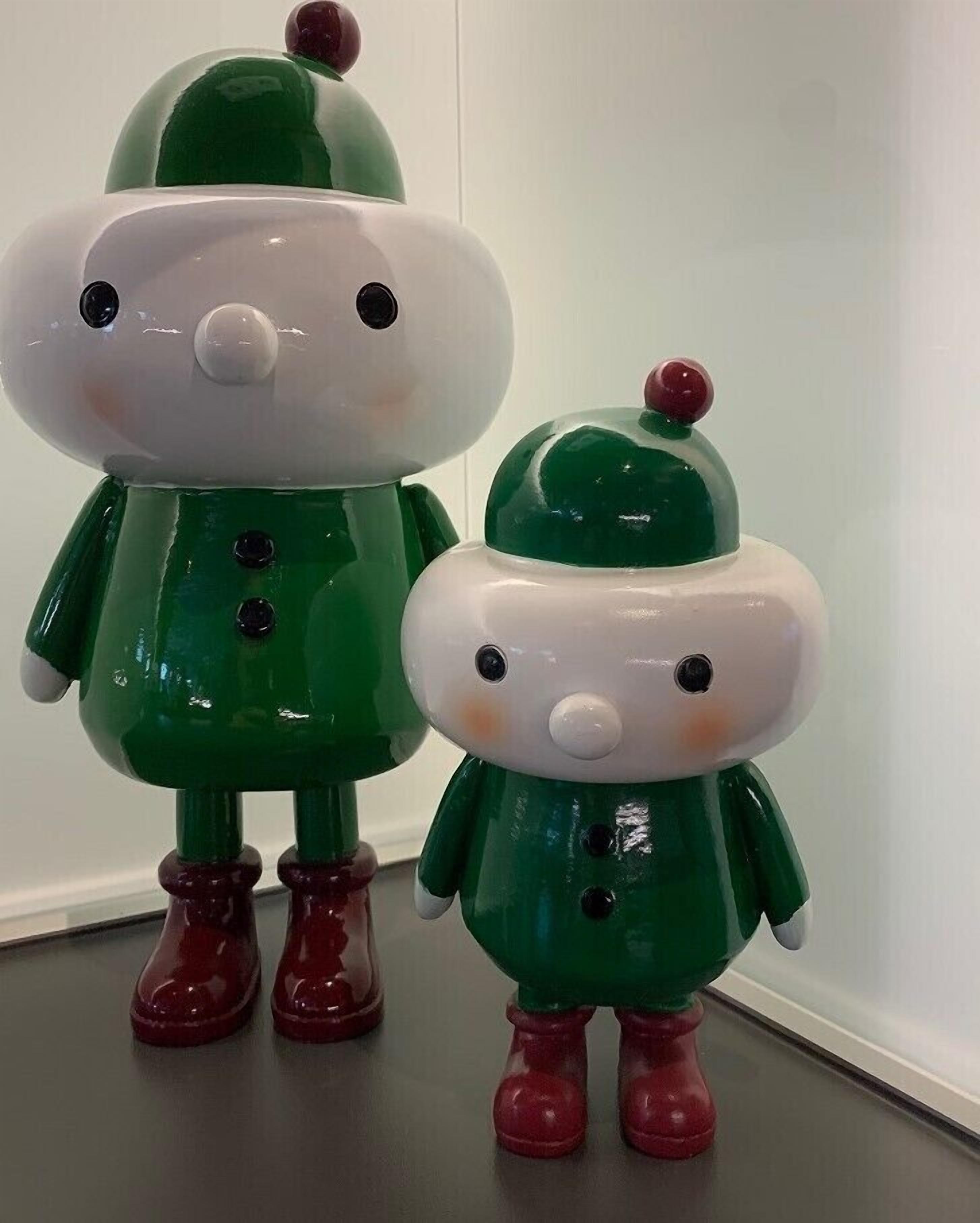 Zwei weihnachtlich gestaltete, grüne und weiße Figuren mit roten Stiefeln.