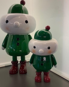 Dos figuritas navideñas en verde y blanco con botas rojas.