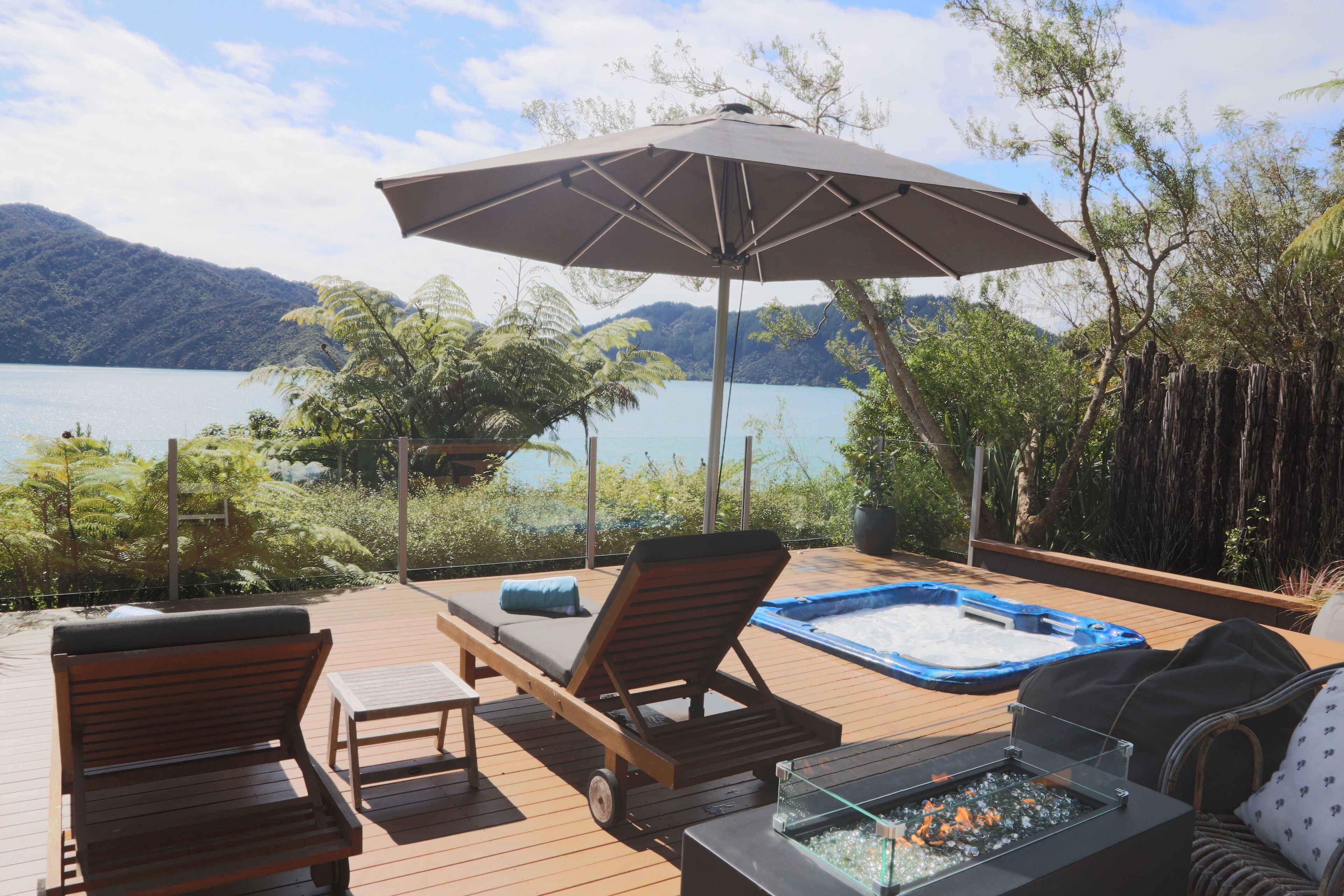 A wooden deck with lounge chairs, a hot tub, and a fire pit.