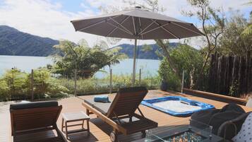 A wooden deck with lounge chairs, a hot tub, and a fire pit.