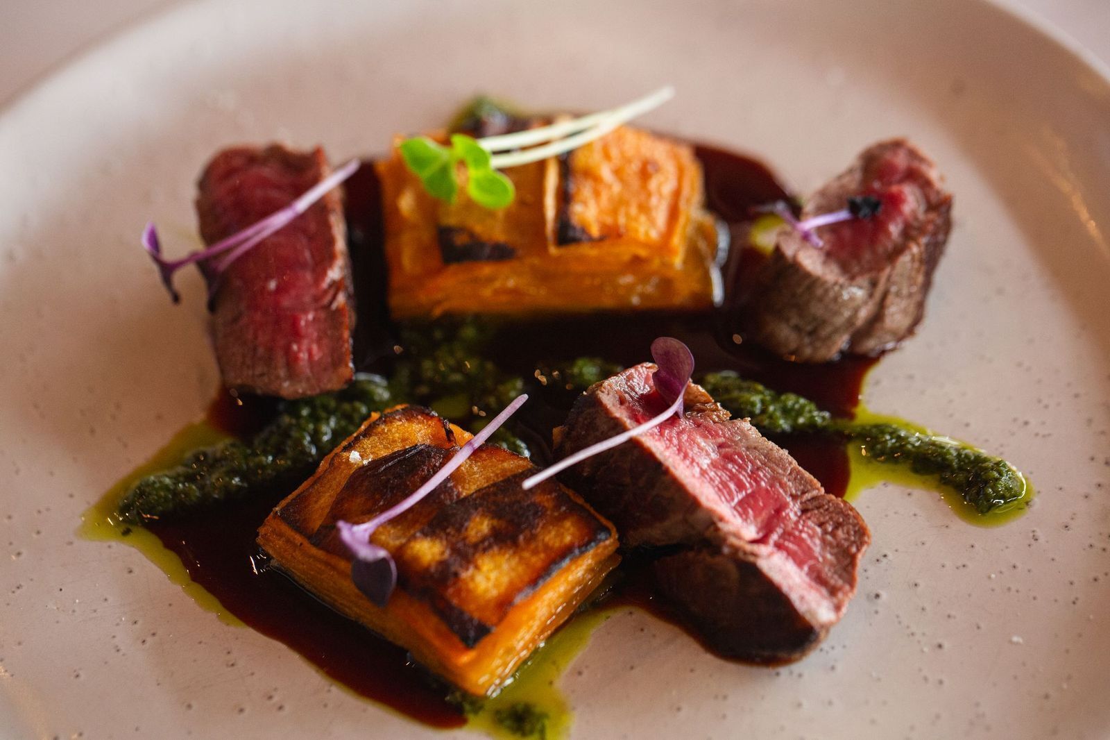 A plated dish with various food items, including what appears to be steak, vegetables, and possibly some greens.