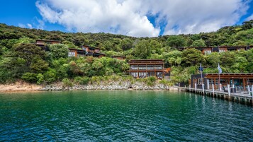 Um imóvel à beira-mar com vários edifícios, um cais e vegetação exuberante.