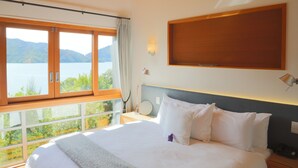 Ein Schlafzimmer mit einem großen Bett, Seeblick und Holzboden.