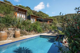 Uma villa moderna com piscina, rodeada por vegetação exuberante e colinas.