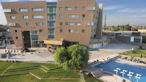 A modern building with multiple floors, a parking area, and a swimming pool. - Del Bono Park Hotel Spa & Casino (San Juan)