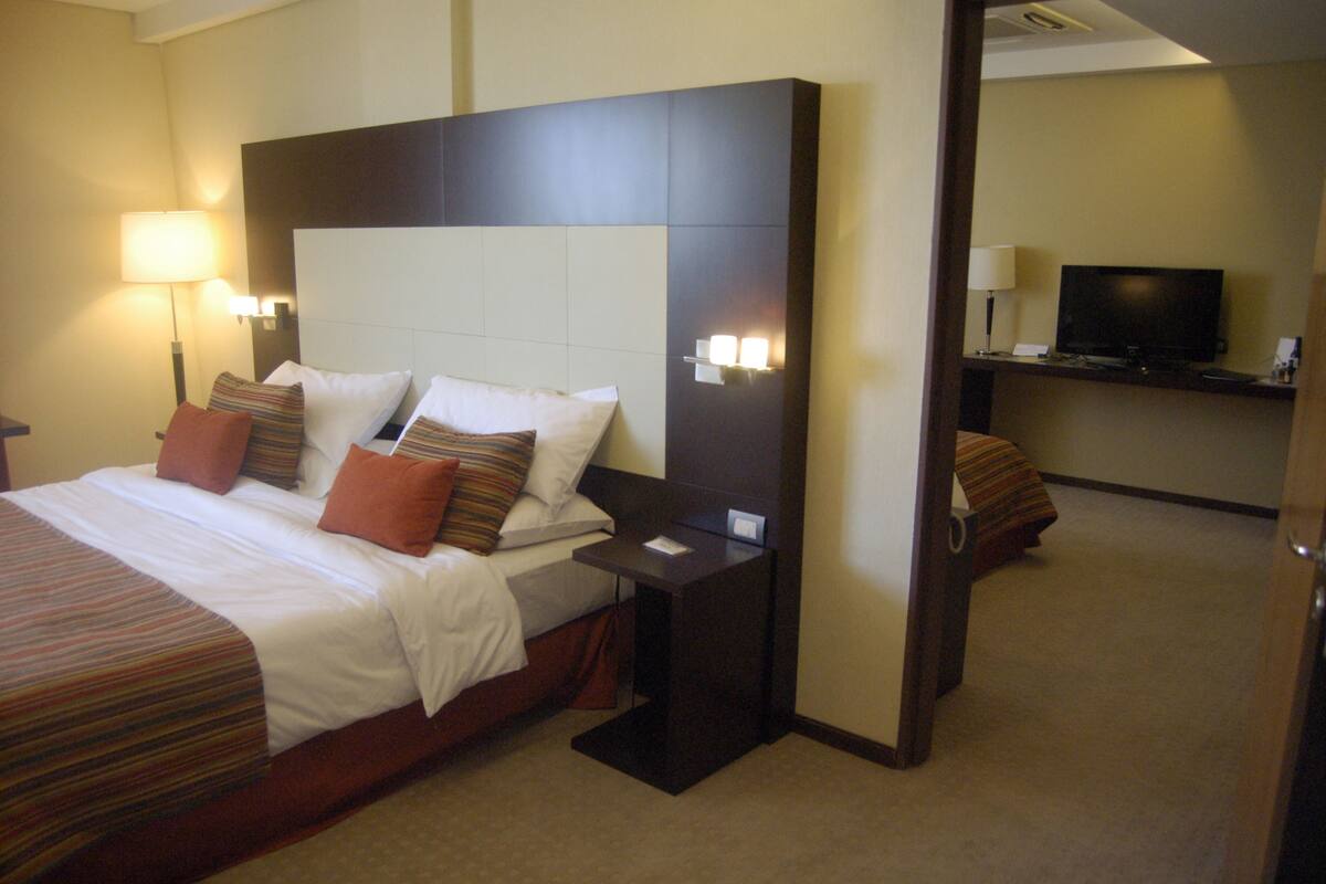 Une chambre d’hôtel avec un grand lit, une table de chevet, une télévision et un bureau.