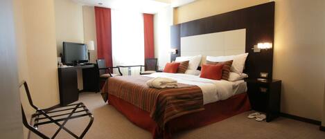Una habitación de hotel con cama, televisor, escritorio y silla.