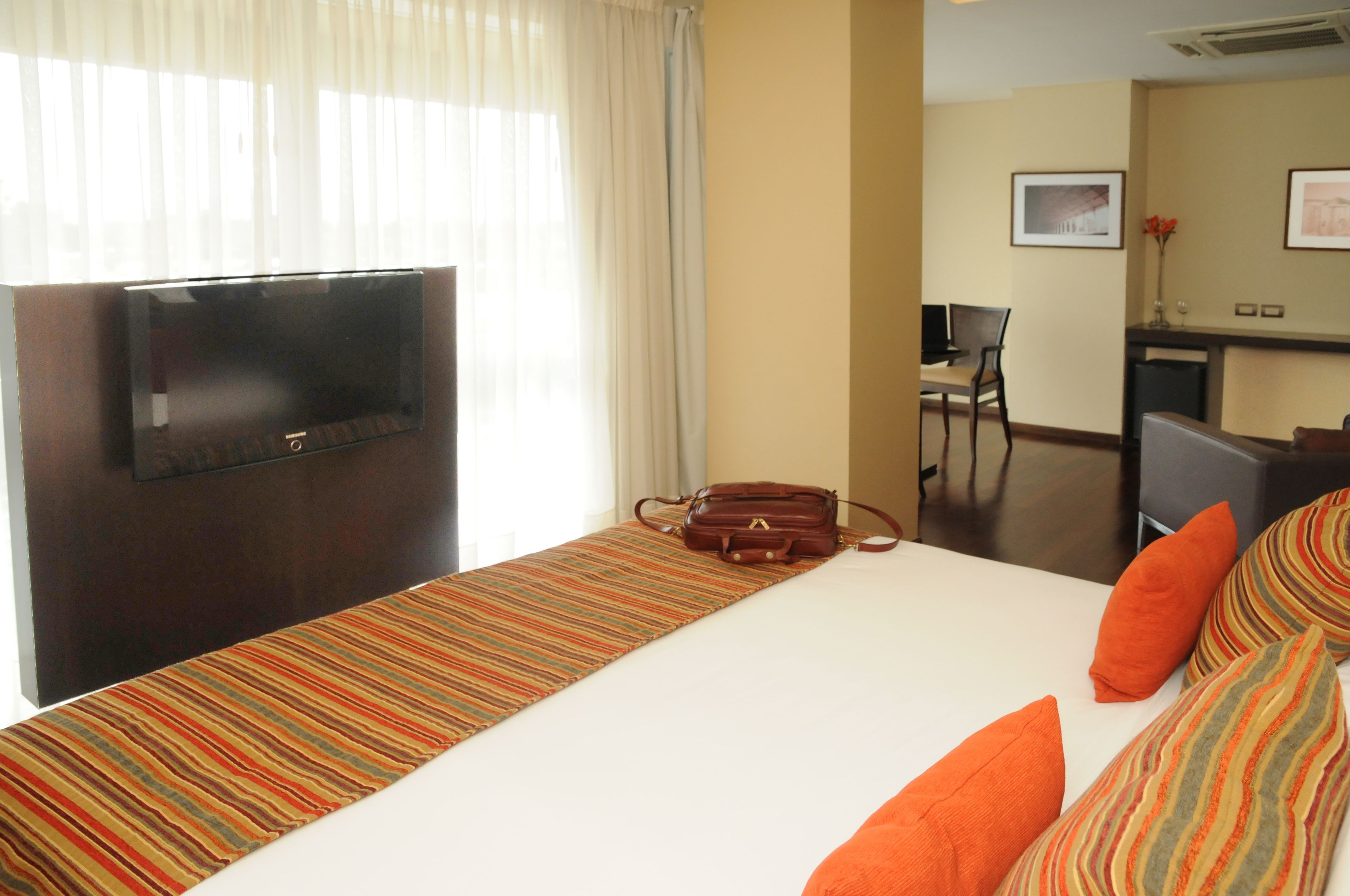 A hotel room with a bed, a TV, a desk, and a chair.