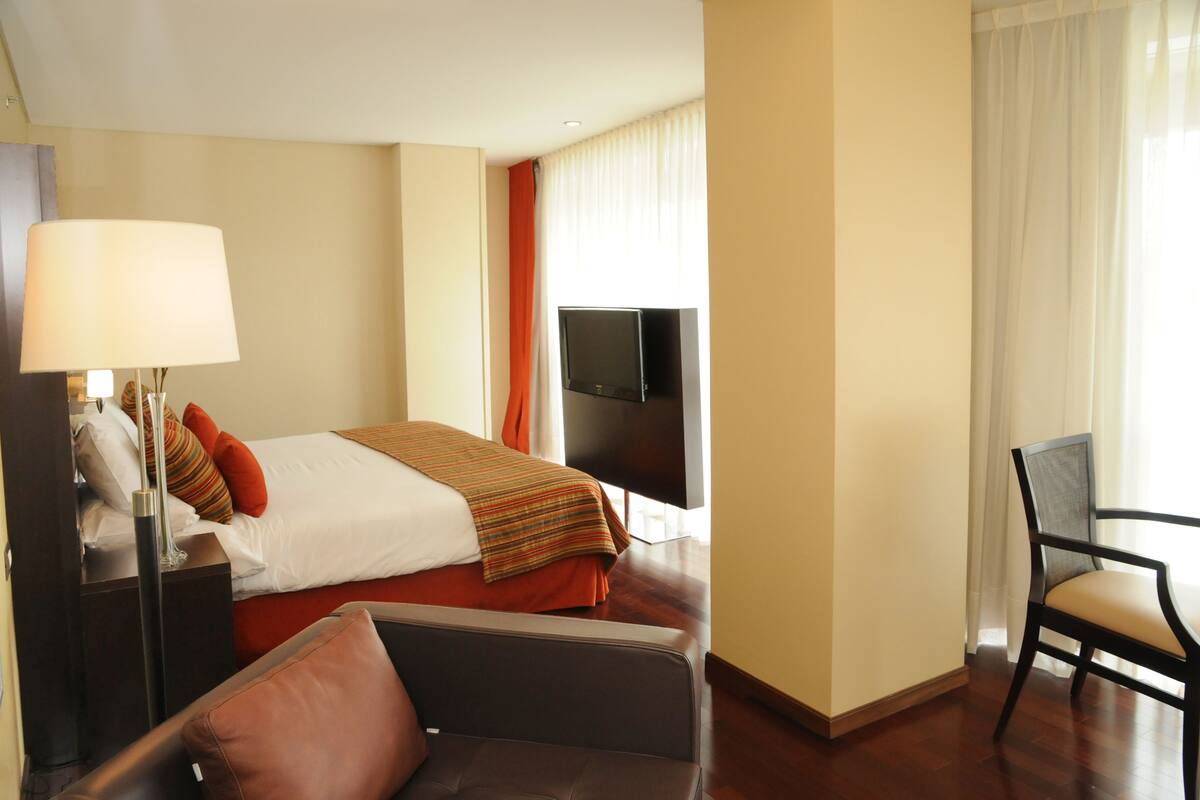 Une chambre d’hôtel avec un lit, une télévision, un bureau avec une lampe et une chaise.