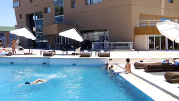 A hotel with a swimming pool, sun loungers, and umbrellas. - Del Bono Park Hotel Spa & Casino (San Juan)