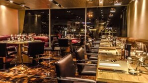 A restaurant with a long counter, multiple tables, and chairs. - Del Bono Park Hotel Spa & Casino (San Juan)