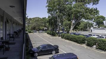 A parking lot with several cars, a building with outdoor seating, and trees in the background.