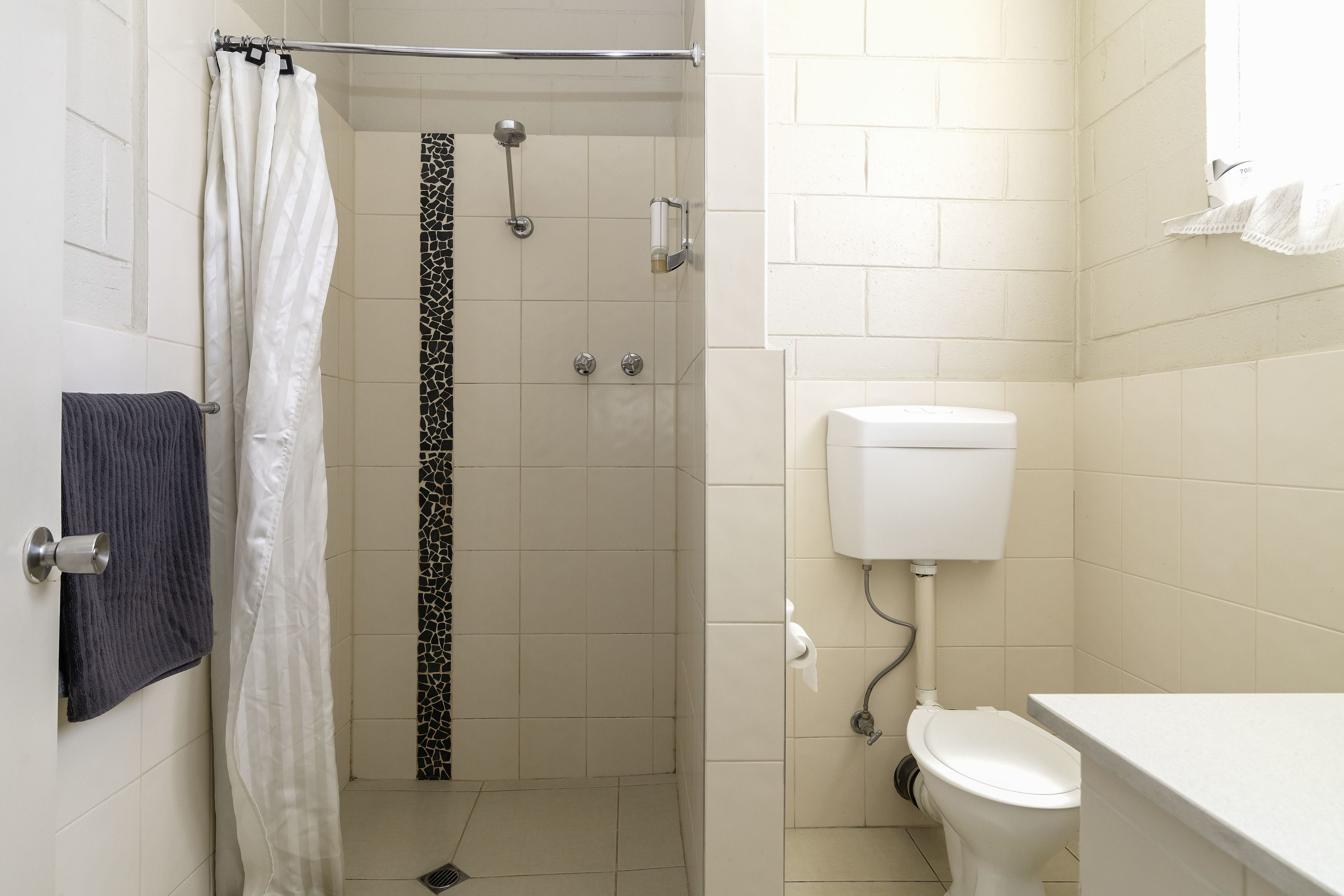 Une salle de bain avec douche, toilettes et lavabo.