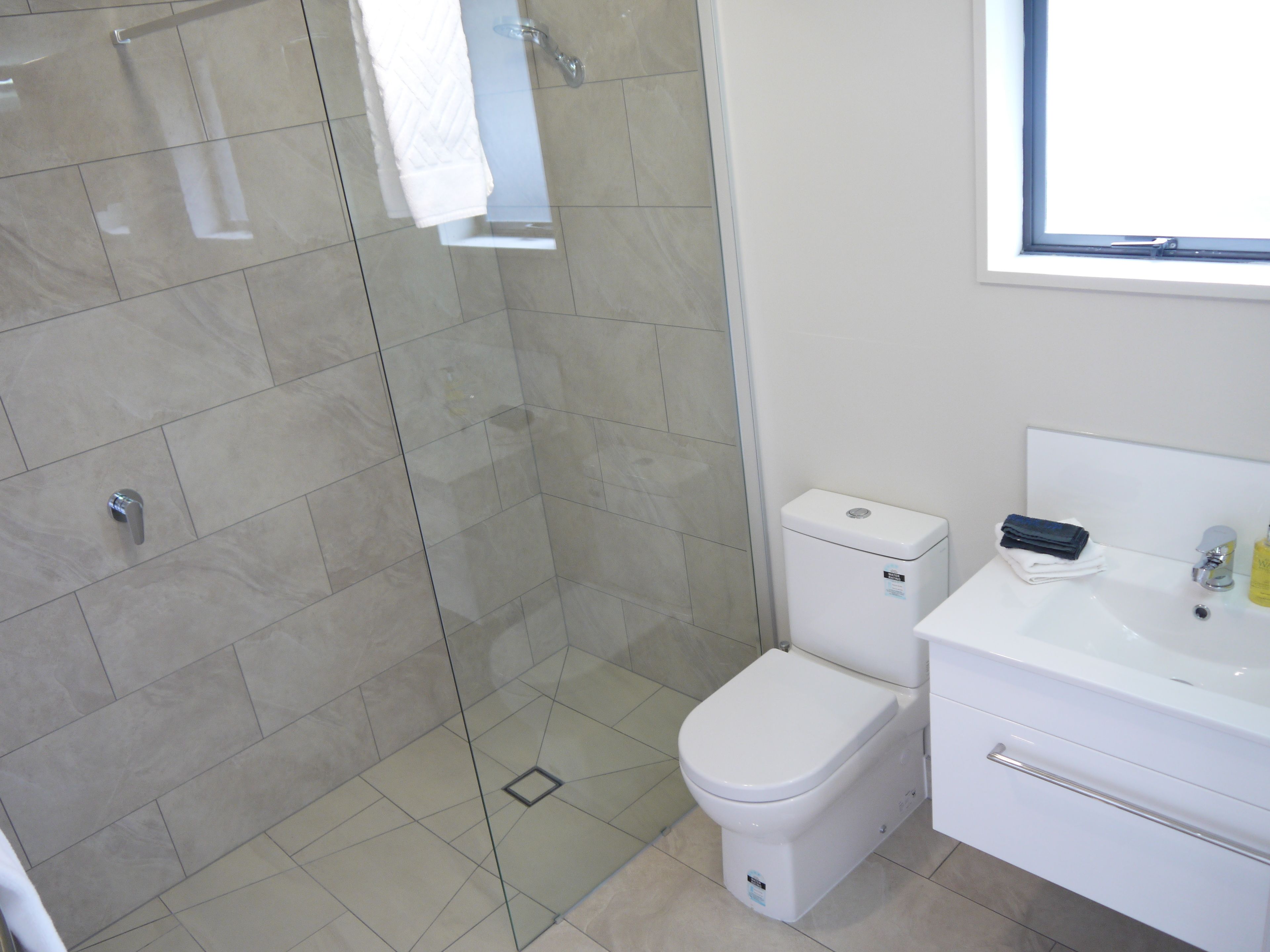 A modern bathroom with a glass shower enclosure, a white toilet, and a sink with a mirror.