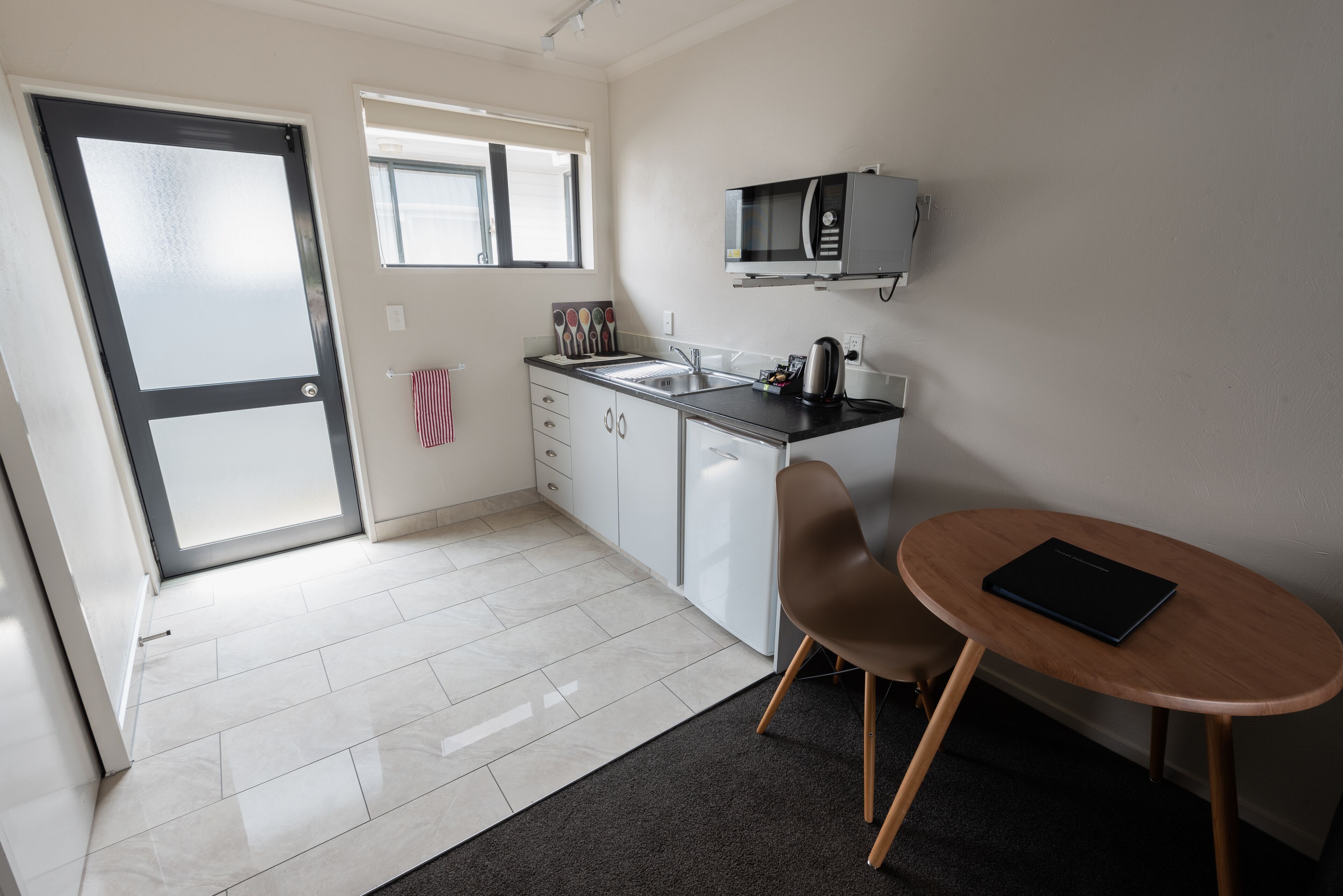 A modern kitchen with a microwave, sink, and a small dining area with a table and chair.