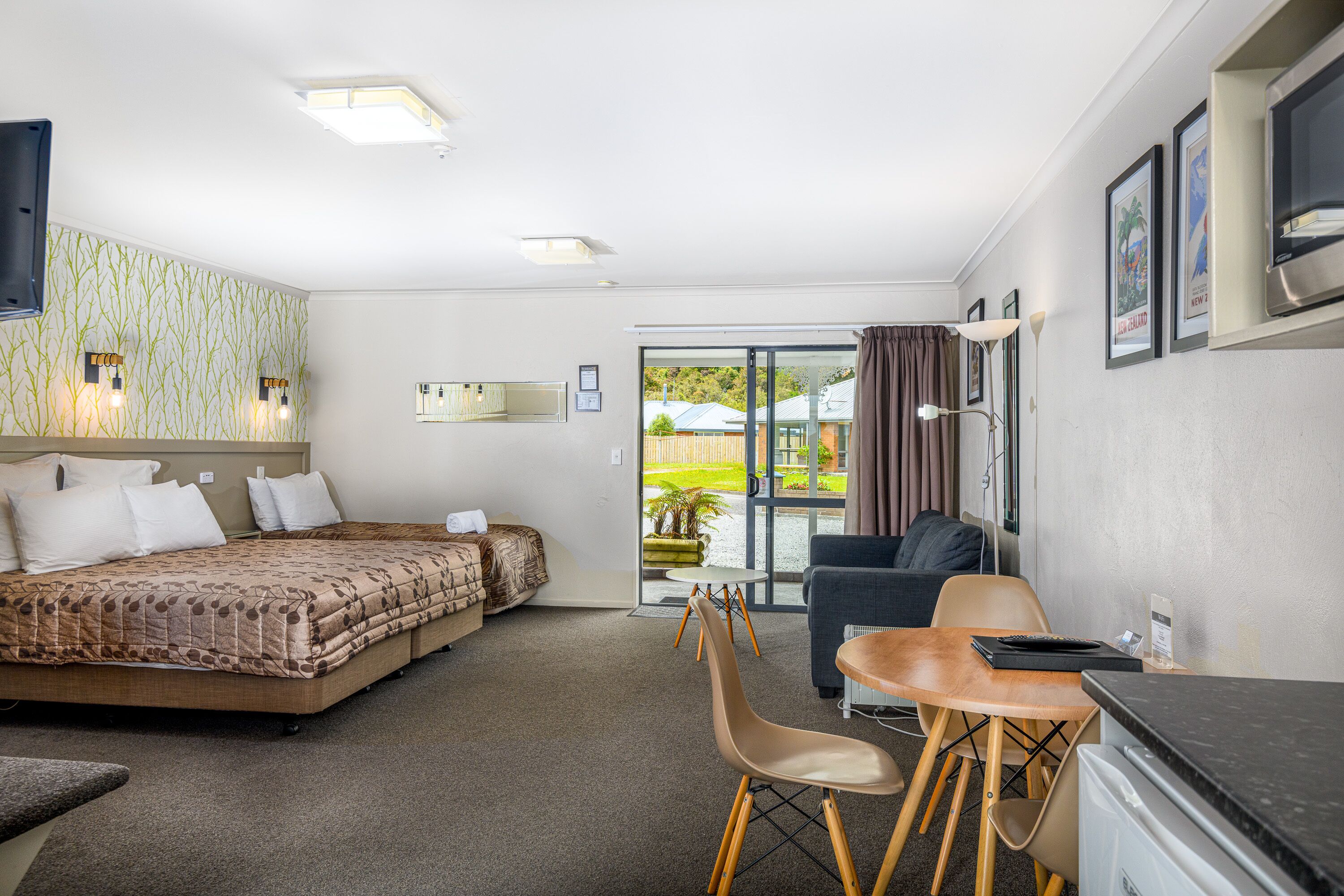 Habitación de hotel con cama, escritorio, silla, televisión y vistas al exterior.