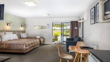 Habitación de hotel con cama, escritorio, silla, televisión y vistas al exterior.