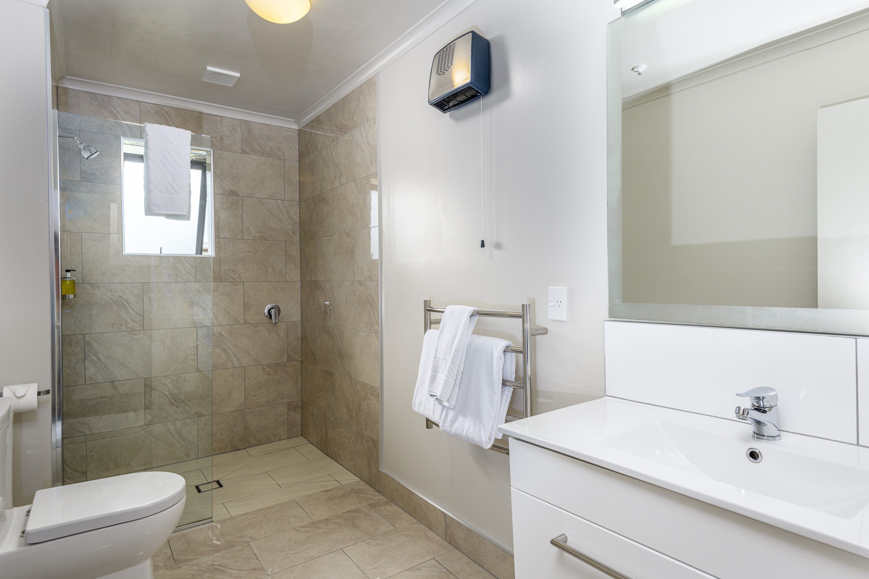 Un baño moderno con ducha, inodoro y lavamanos.