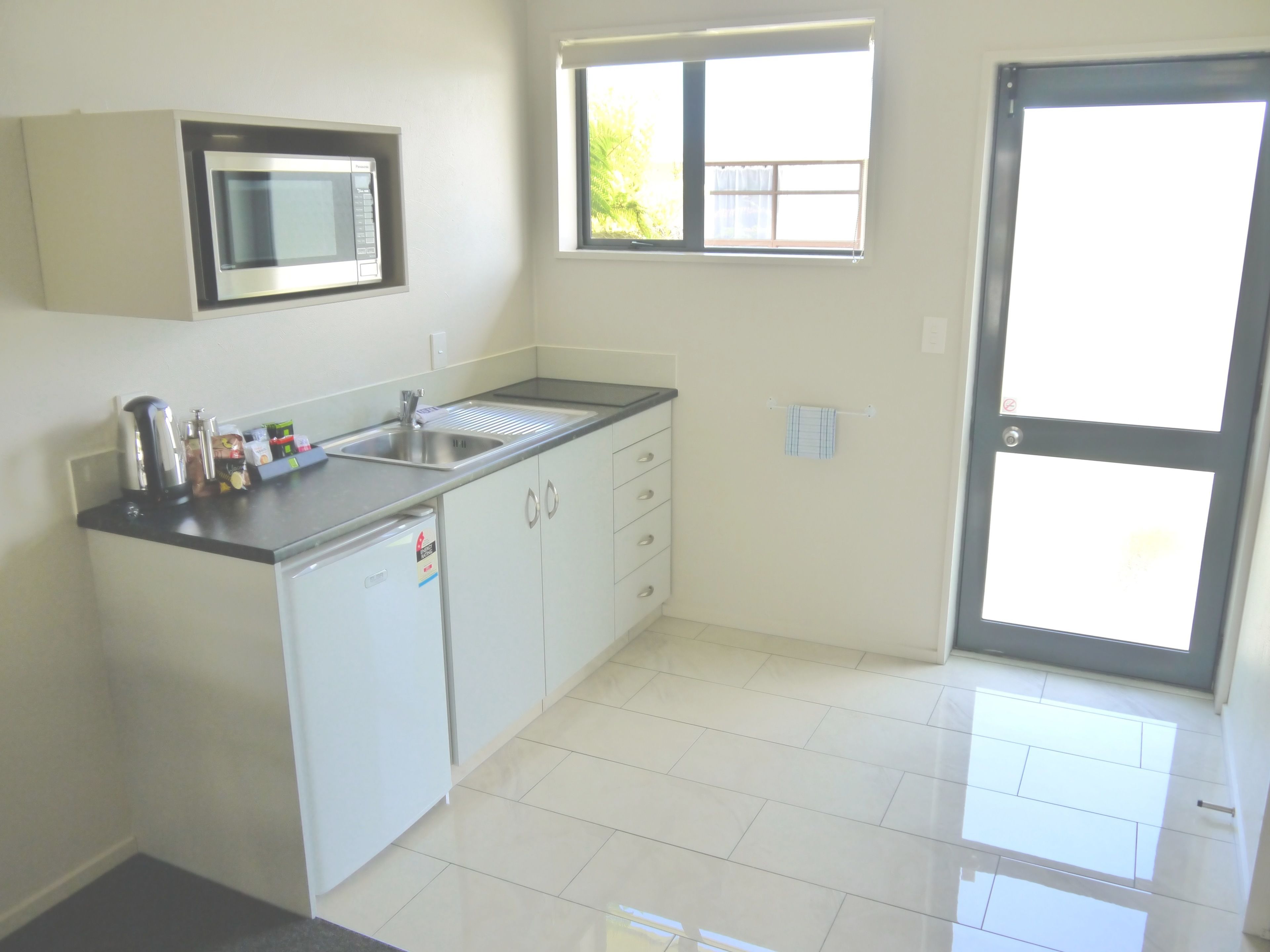 A modern kitchen with a built-in microwave, a sink, and a compact dishwasher.