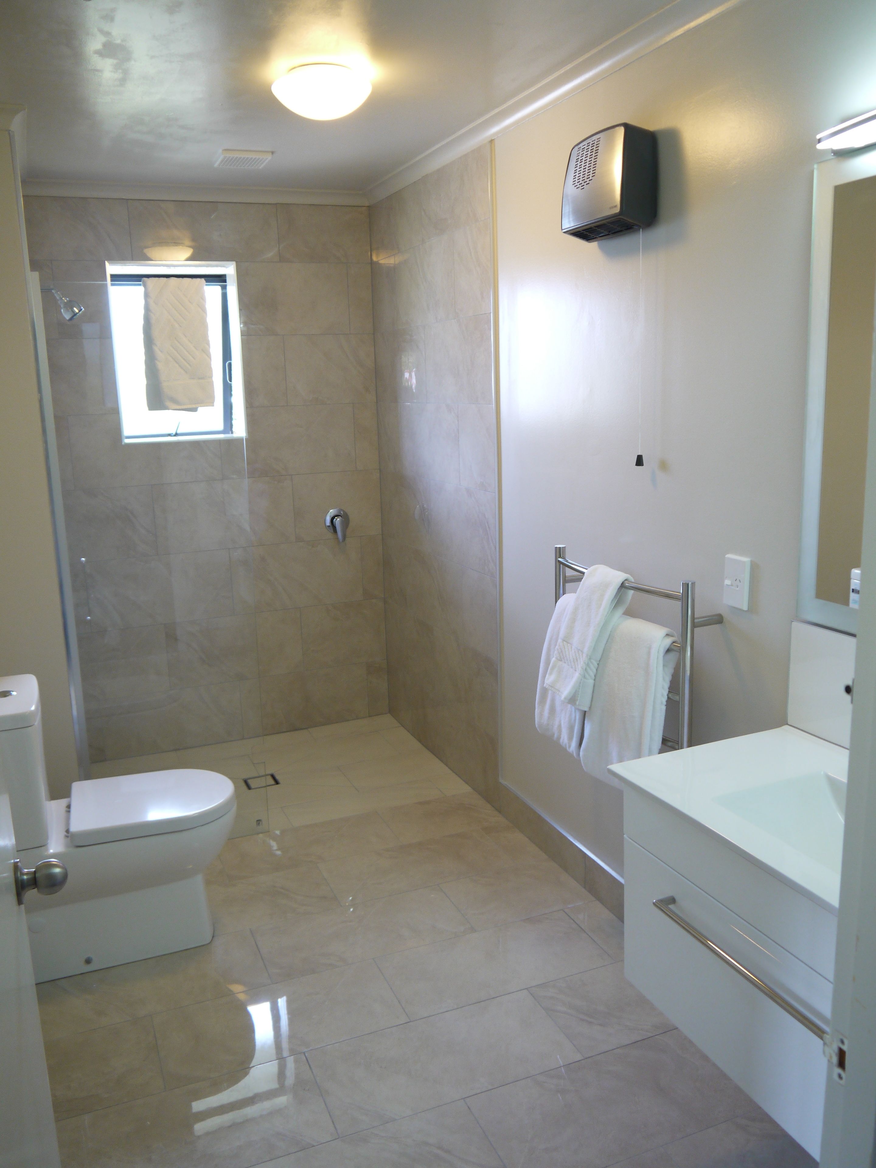 A modern bathroom with a toilet, shower, and sink.
