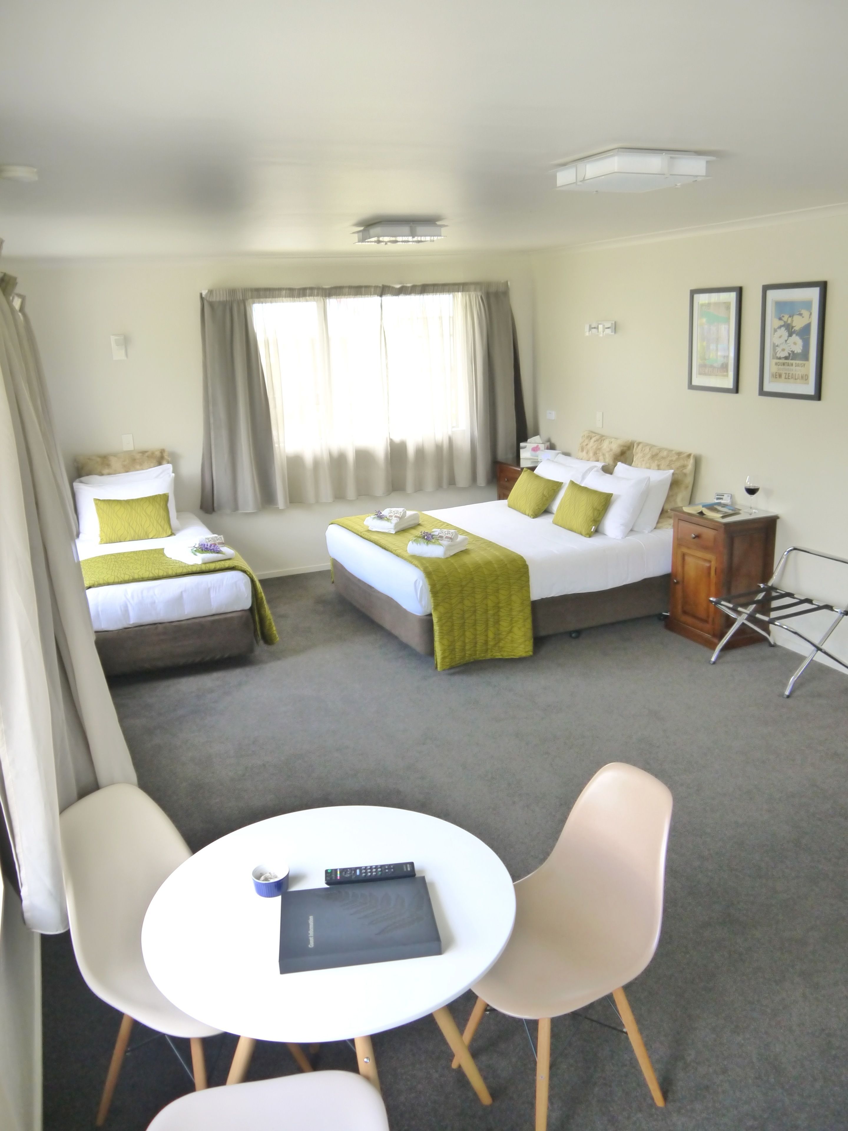 A hotel room with two beds, a small table, and chairs.
