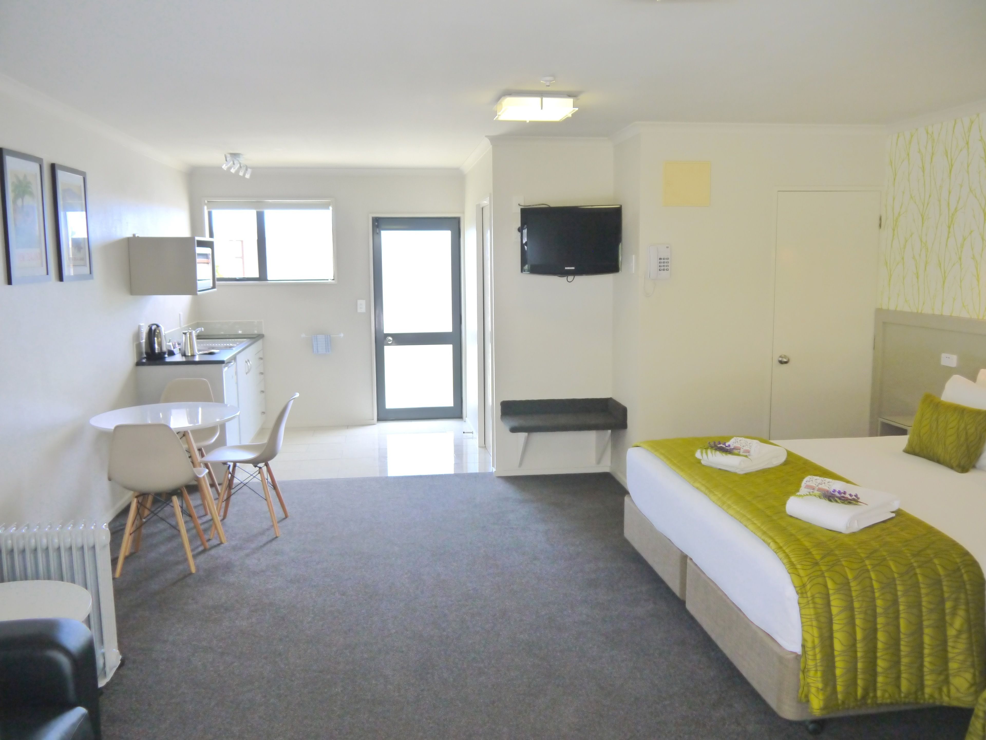 A hotel room with a bed, a desk, a chair, a television, and a bathroom door.
