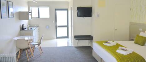 A hotel room with a bed, a desk, a chair, a television, and a bathroom door.