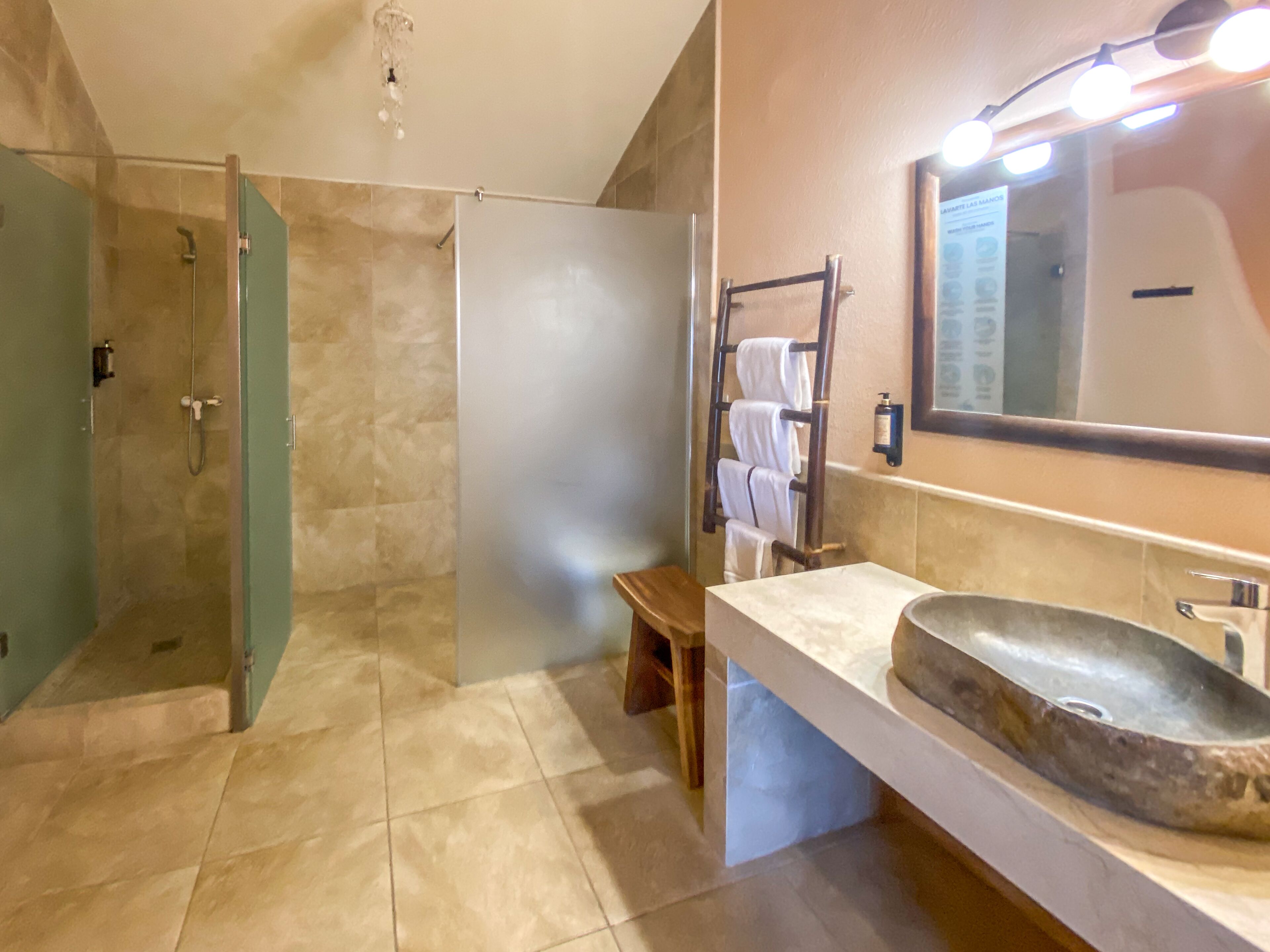 Ein Badezimmer mit bodengleicher Dusche, einem Waschtisch mit großem Becken und einem Handtuchhalter.