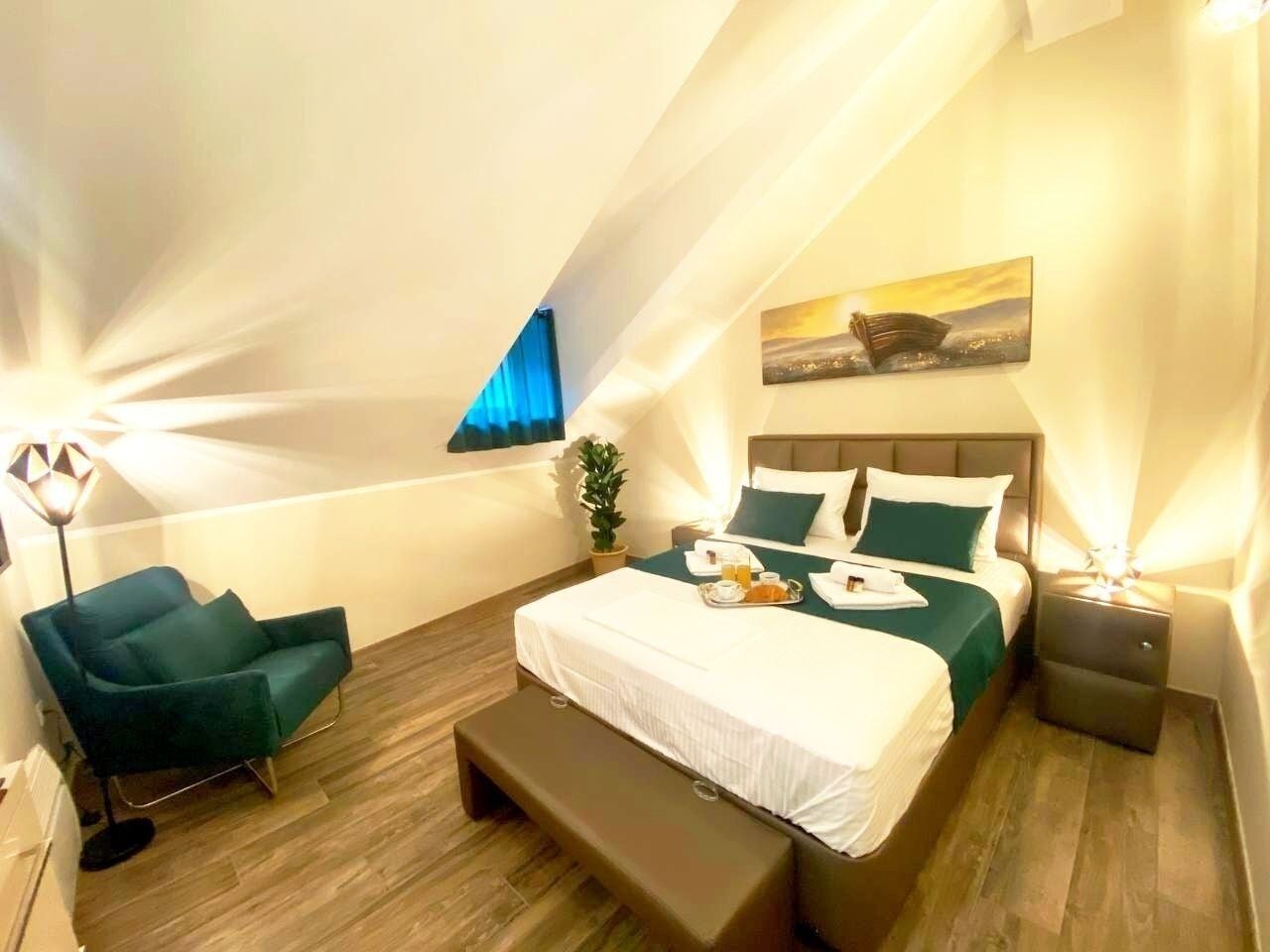 Une chambre moderne avec un grand lit, un banc, une chaise et une table de chevet.