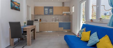 A compact living space with a kitchenette, a dining area, and a sofa with cushions.